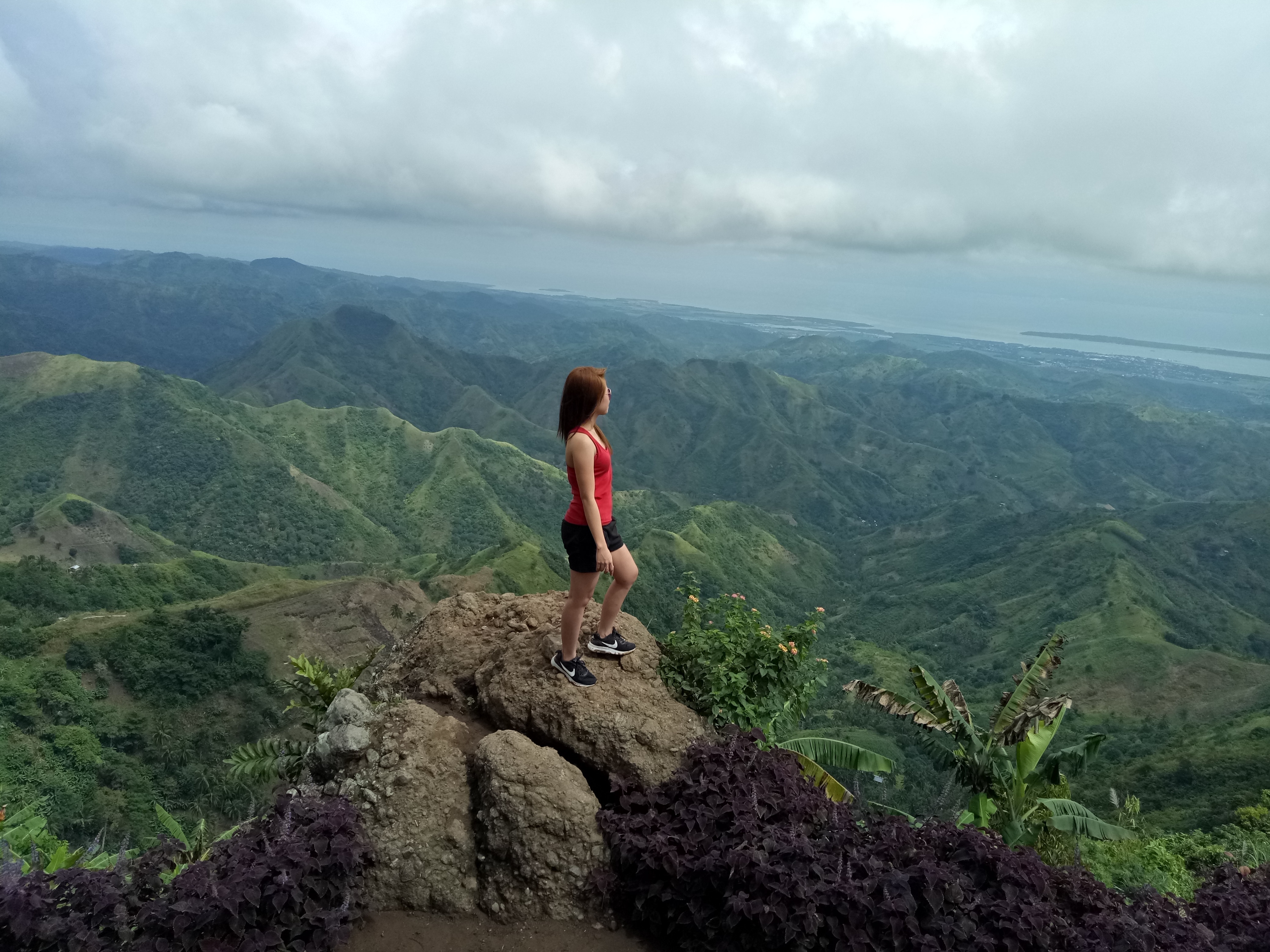A woman standing on top of a mountain, looking proud.